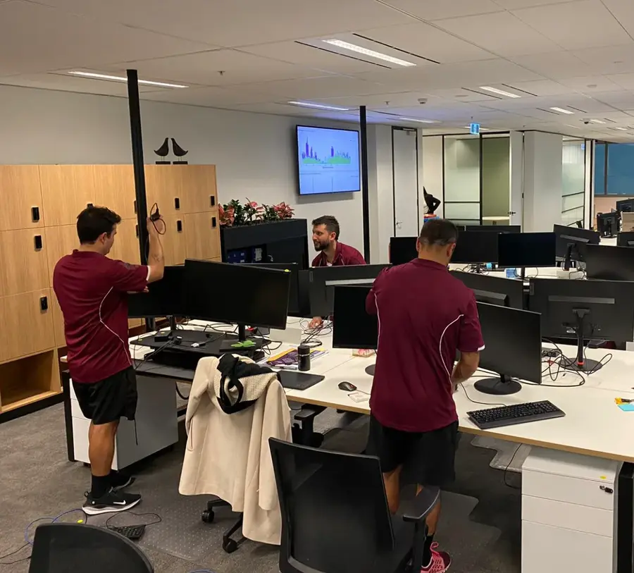 Posch & Silva movers setting up desks and monitors in an open-plan office